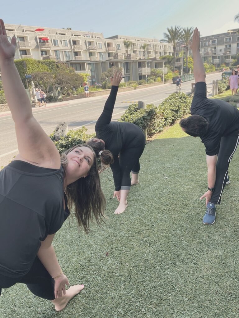 Three people in a side bend on the grass