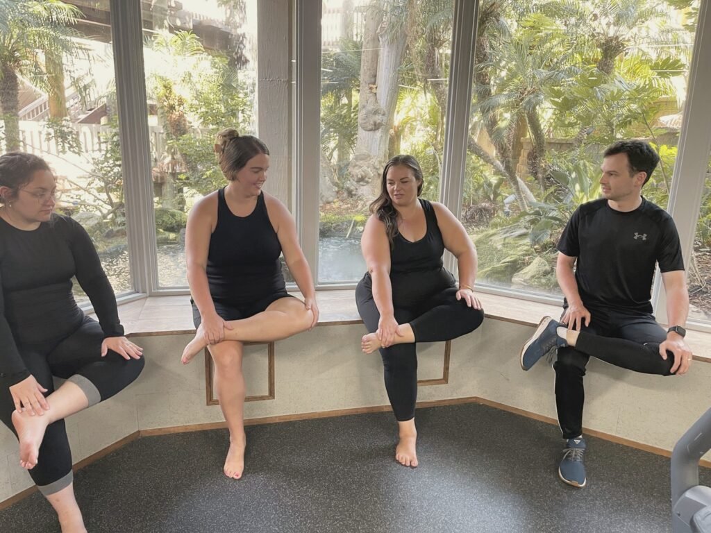 A group seated on a window bench in a seated hip stretch