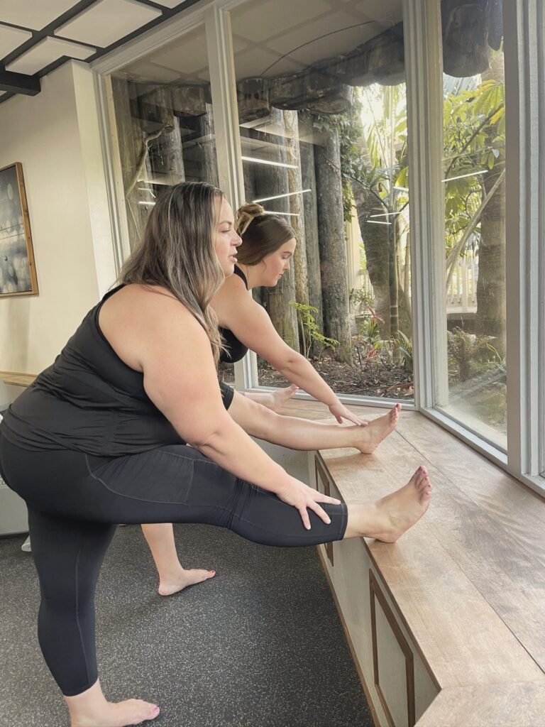 Two women stretching one leg along a window bench
