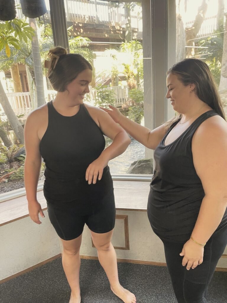 An instructor guiding a woman's arm position as they both smile