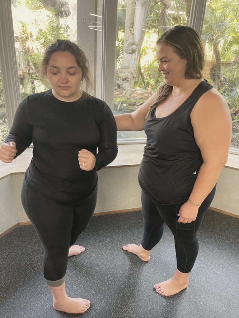 An instructor resting a hand on a woman's shoulder as she balances