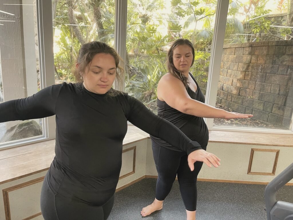 Two women sweeping their arms out to the side