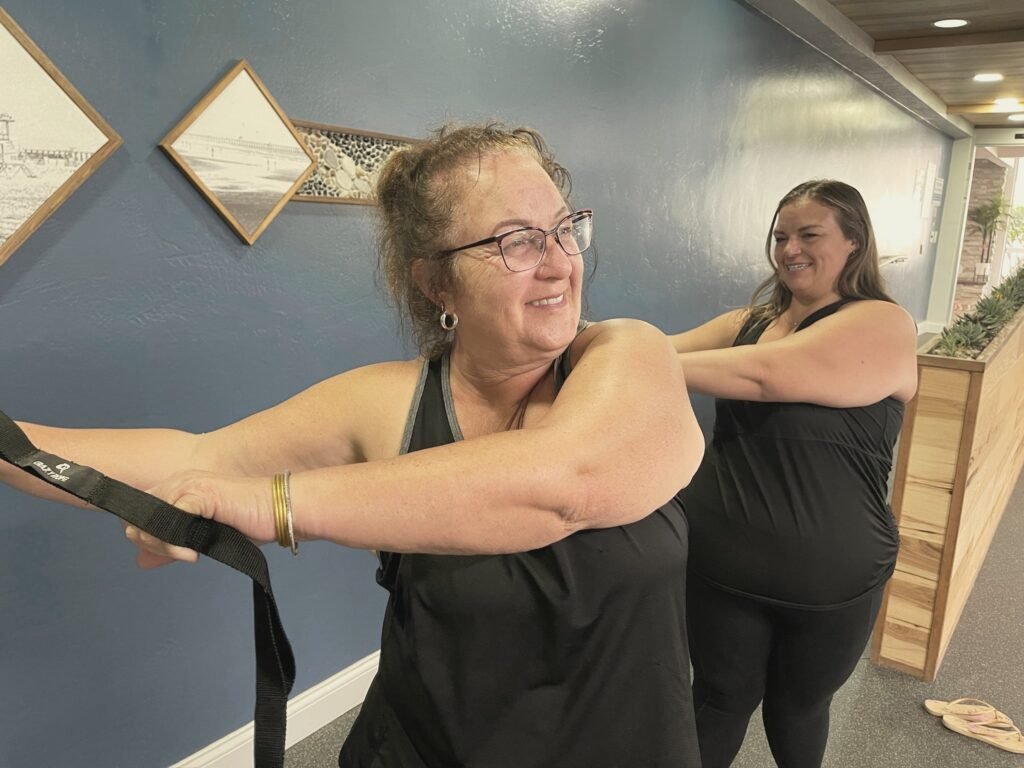 A woman smiling as she holds a stretch strap at arm's length